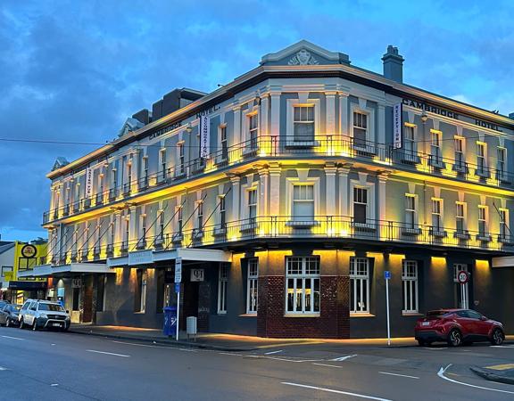 The Cambridge Hotel in Wellington. The hotel is housed inside a low-rise, corner-site public house building designed in the inter-war period.