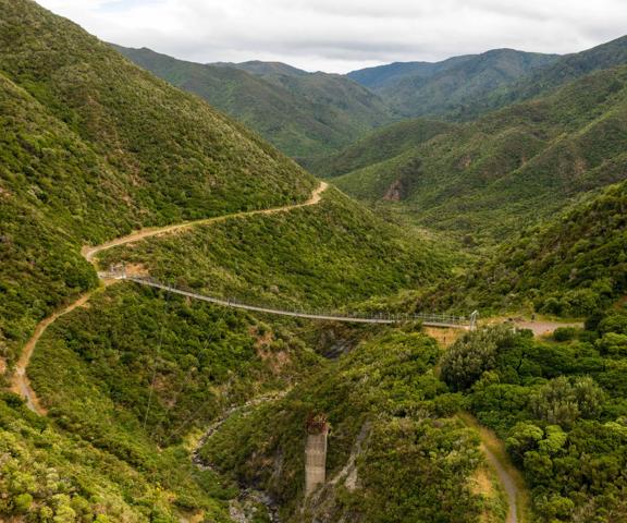 Looking into a valley in the Remutaka Range, where the Remutaka Cycle trail and swingbridge can be seen.