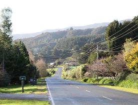 Mangaroa Valley Road screen location, a scenic rural setting with native forest, farmland, and a mountainous backdrop.