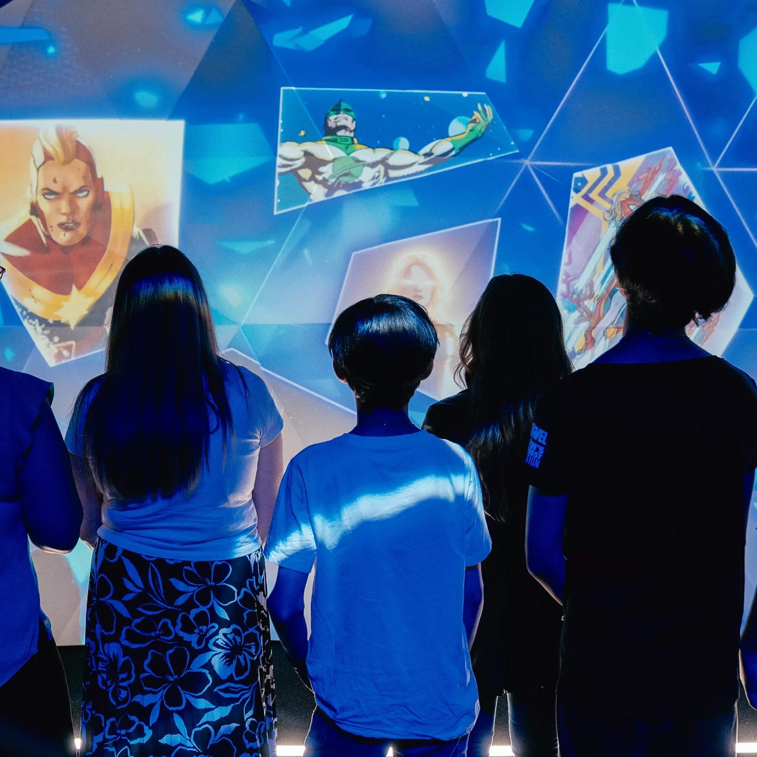 A group of people standing in front of an illuminated display at Marvel: Earth's Mightiest Exhibition at Tākina.