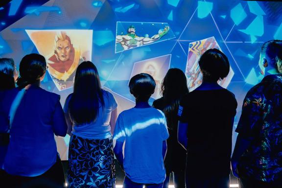 A group of people standing in front of an illuminated display at Marvel: Earth's Mightiest Exhibition at Tākina.