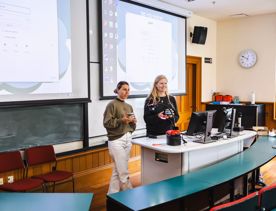 Two students present their project inside a lecture hall.