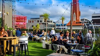 Customers enjoy the sun, eat, and drink at the rooftop bar of Trinity Hotel, The Arborist.