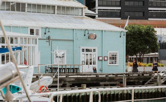 Shed 5 - a blue wharf building is perched on the edge of the waterfront in Wellington.
