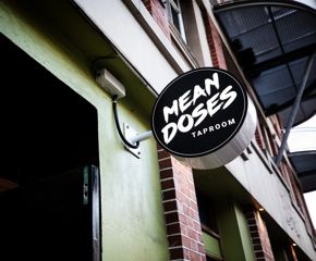 The sign above the entrance at Mean Doses Taproom. It's a circular sign with white font on a black background.