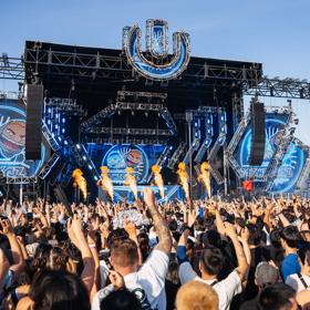 An outdoor stage at ULTRA Worldwide Music Festival in Melbourne, Australia, with huge screens, speakers, pyrotechnics, and a packed cheering audience.