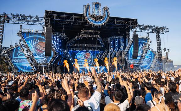 An outdoor stage at Ultra Worldwide Music Festival in Melbourne, Australia, with huge screens, speakers, pyrotechnics, and a packed cheering audience.
