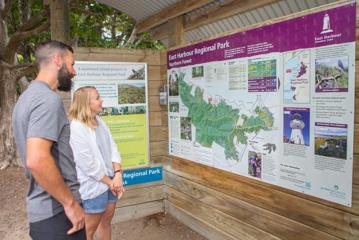 Two people look at a Map of East Harbour Regional Park.