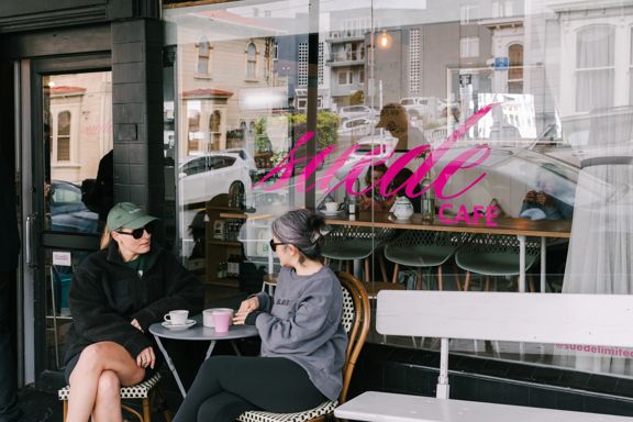 People enjoying coffee outside Suede Café’s street-front window.