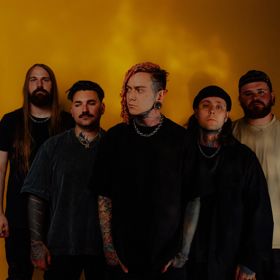 Five band members of Lorna Shore stand in front of a yellow-orange wall.