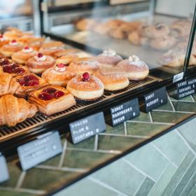 Rows of assorted pastries in a glass display case on a green-tiled counter top. 