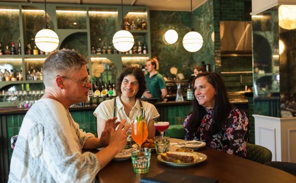 Three friends enjoy food and drinks at Hummingbird Restaurant and Lounge.