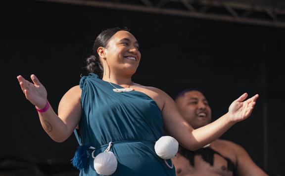 Person in a teal dress with two poi attached to their waist.