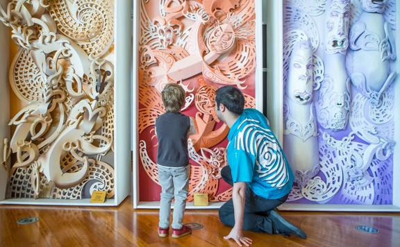 A tour guide shows a child the designs on the walls of Rongomaraeroa in Te Papa Museum Te Marae.