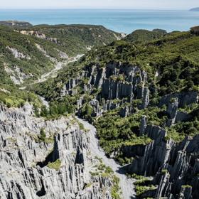 Image of the Pūtangirua Pinnacles. Taken from a drone, looking down on the large stalagmite structures, with Palliser Bay in the background.