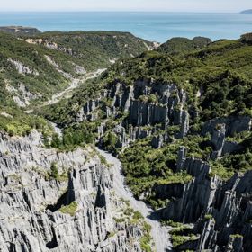 Image of the Pūtangirua Pinnacles. Taken from a drone, looking down on the large stalagmite structures, with Palliser Bay in the background.