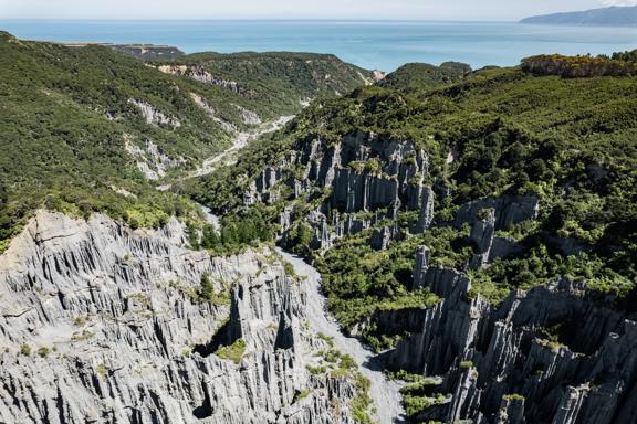 Image of the Pūtangirua Pinnacles. Taken from a drone, looking down on the large stalagmite structures, with Palliser Bay in the background.
