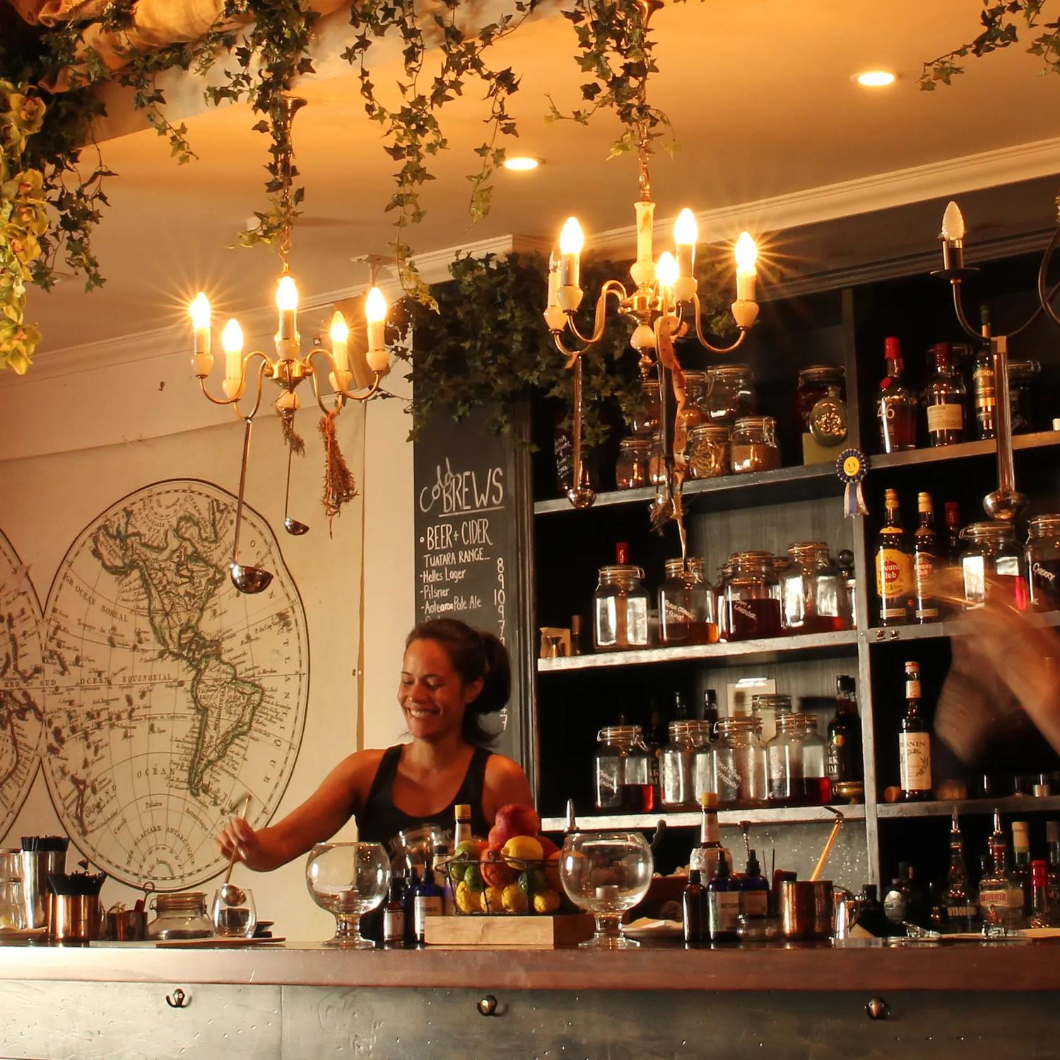 Inside CGR Merchant & Co. a hidden bar on Courtenay Place in Wellington. Two bartenders are mixing drinks behind the counter. 