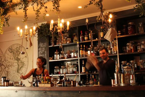 Inside CGR Merchant & Co. a hidden bar on Courtenay Place in Wellington. Two bartenders are mixing drinks behind the counter. 