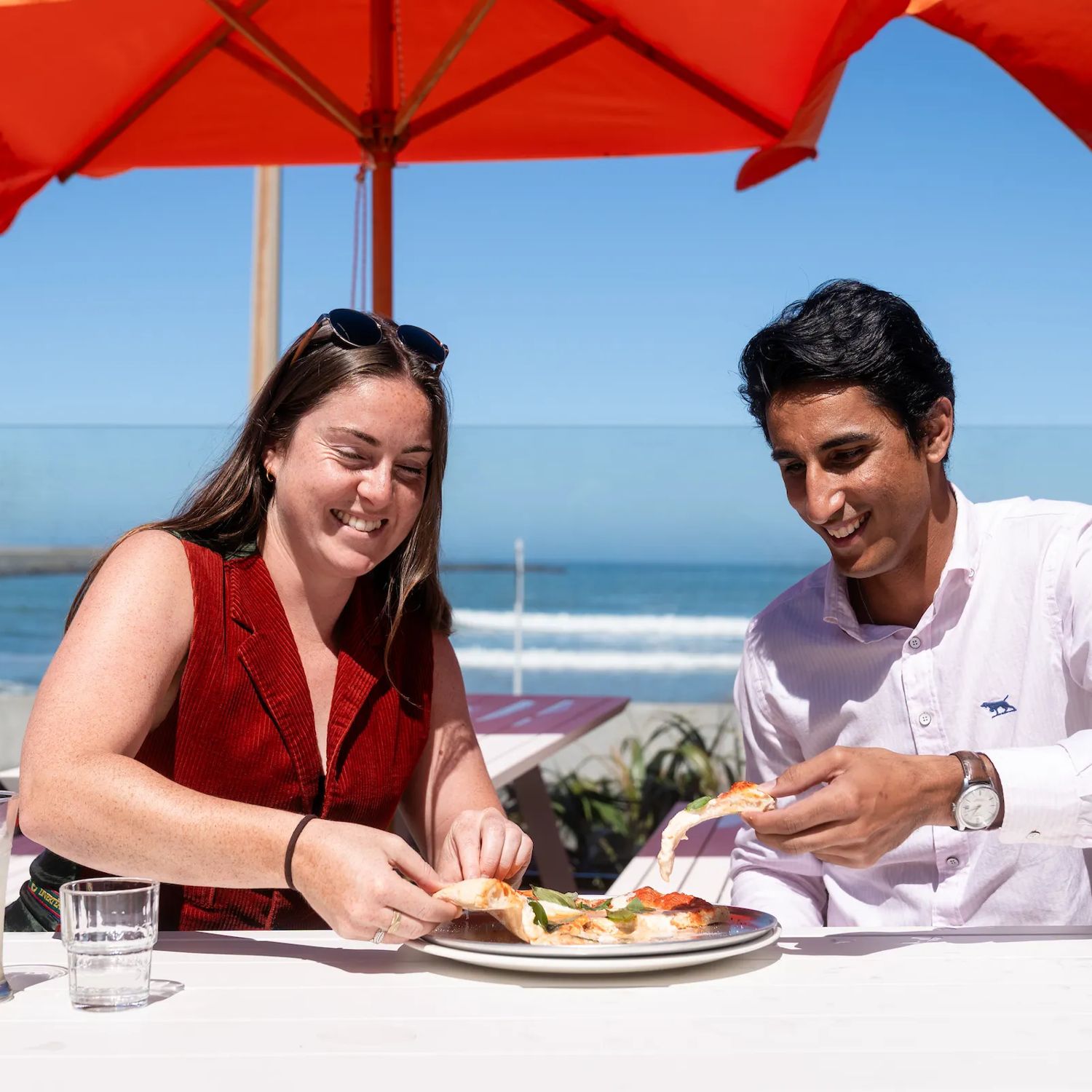 Two people enjoying pizza in the sun at Hotel Catalina.