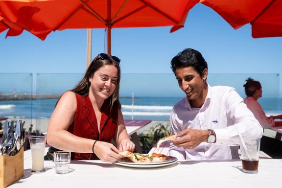 Two people enjoying pizza in the sun at Hotel Catalina.