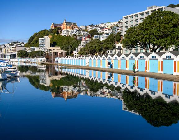 The screen location of Oriental Bay, wth pastel-coloured, Art Deco apartments, brightly-painted boat sheds, and the golden beach.