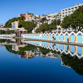 The screen location of Oriental Bay, wth pastel-coloured, Art Deco apartments, brightly-painted boat sheds, and the golden beach.