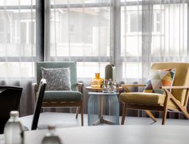 Water bottles and glass on top of a coffee table, chairs around the coffee table inside WQ Hotel