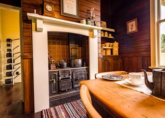 Inside the kitchen at Katherine Mansfield House & Garden. The room has wood panelled walls and Victorian-era housewares.