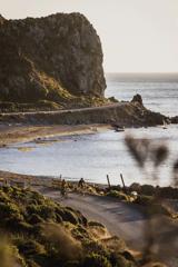 Two cyclists ride along Pencarrow Coast Road in Wellington, New Zealand.