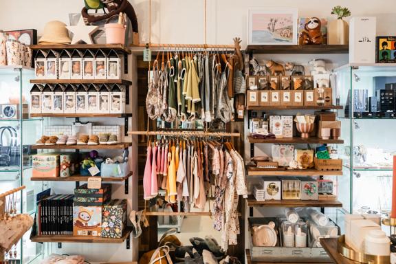 Inside Cre8iveworx boutique shop wooden shelves filled with children's books, toys and clothes for sale.