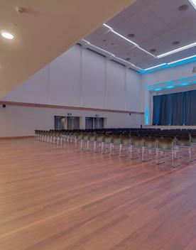 The huge room inside Lower Hutt Events Centre, with hundreds of chairs facing a stage, large curtains, and very high ceilings.