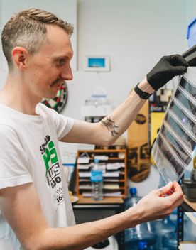 A person in a white teeshirt looks at a sheet of photo negatives.