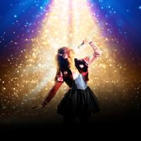 Juliet wears pink headphones, holds a microphone and sings in a sparkly spotlight.