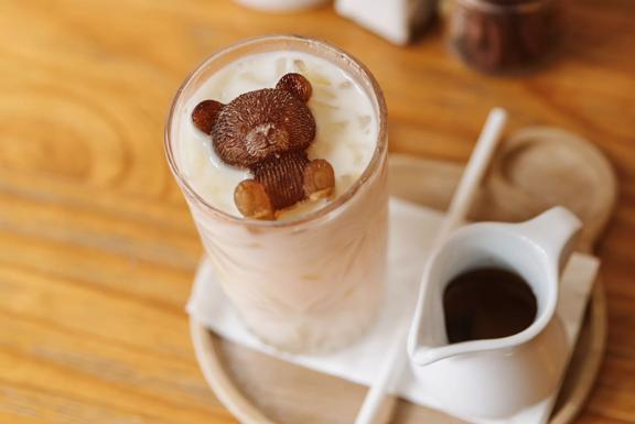 Looking down on an iced coffee made by Gemini Cafe & Eatery, a glass of iced milk with a chocolate bear sits to the left and a little shot of espresso next to it.