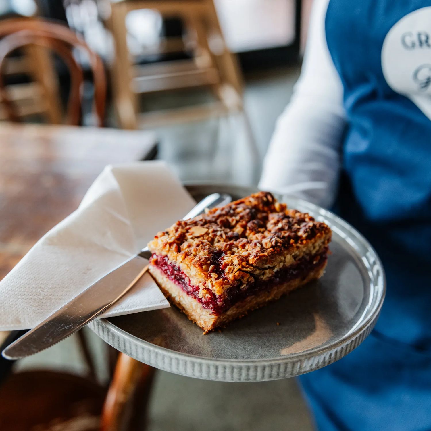 A server holds a plated pastry at Gravel & Grace.
