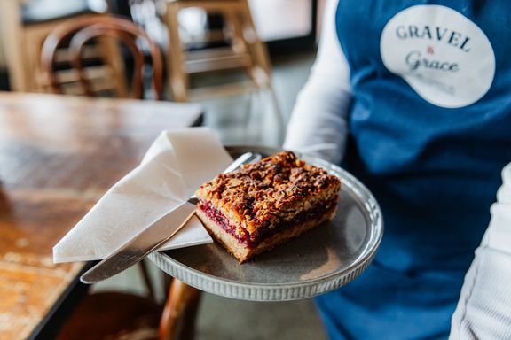 A server holds a plated pastry at Gravel & Grace.