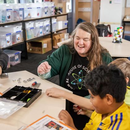 3 children and an adult sit at table at House of Science and play with magnets.
