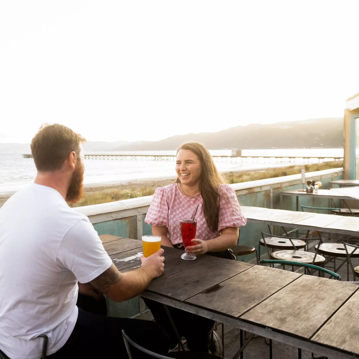 Two people enjoying drinks on the patio of Seashore Cabaret, a café and restaurant located on the Esplanade in Petone, Lower Hutt. 