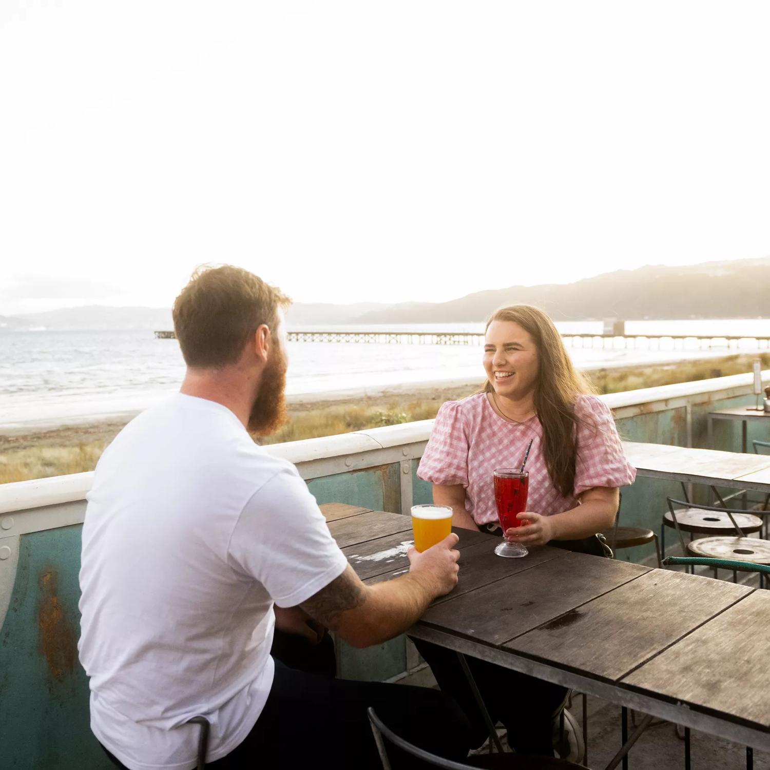 Two people enjoying drinks on the patio of Seashore Cabaret, a café and restaurant located on the Esplanade in Petone, Lower Hutt. 