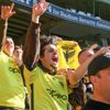 Fans cheering at the stadium while wearing yellow Phoenix jerseys