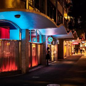 The exterior of Concord at night, with blue and red lights lighting up with building and a person standing outside.