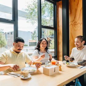 Three friends enjoy brunch at Prefab eatery on a sunny day in Wellington.