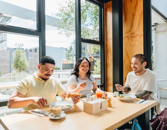 Three friends enjoy brunch at Prefab eatery on a sunny day in Wellington.