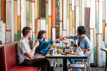 Three people eat crab and other seafood plates at The Crab Shack on Queens Wharf.