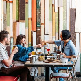 Three people eat crab and other seafood plates at The Crab Shack on Queens Wharf.