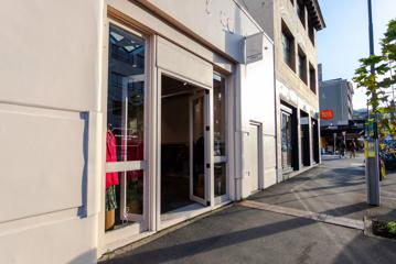 The storefront of a boutique clothing store. It's a white building with glass doors.