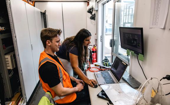 2 people working on a computer in hi-vis at an Engineering firm.