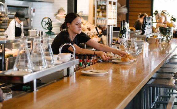 A worker placing plates of food onto a counter at Prefab Eatery.