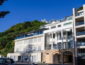 The screen location of Oriental Bay, wth pastel-coloured, Art Deco apartments, brightly-painted boat sheds, and the golden beach.